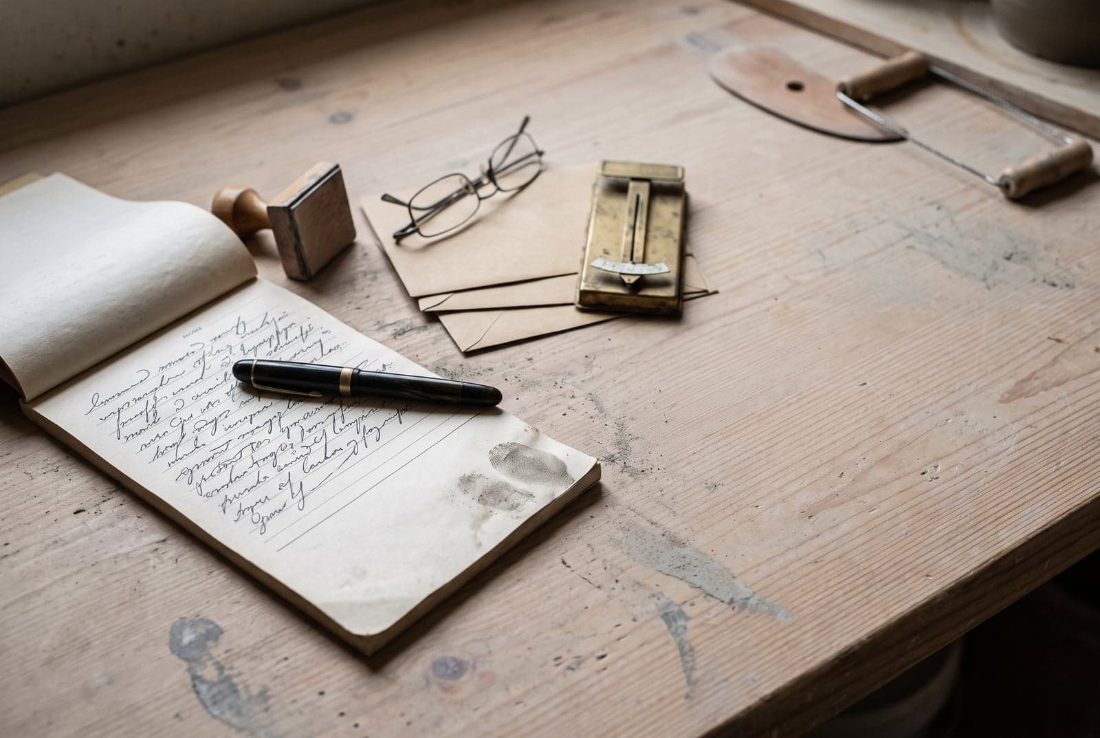 Carnet à souches, tampon en bois, lunettes et enveloppes sur l'établi poussiéreux d'un atelier de poterie