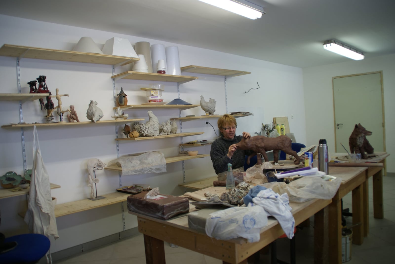 Vue intérieure de l'atelier : étagères de pièces en cours de séchage et tables de travail